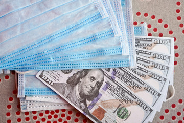 Medical masks with money. American dollars with protective masks. A fan of dollars with a fan of...