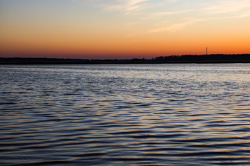 Fototapeta premium Beautiful landscape view with river slowly flowing with small waves during the sunset.