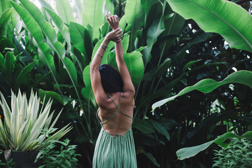 Fit woman in green dress among exotic green shrubs