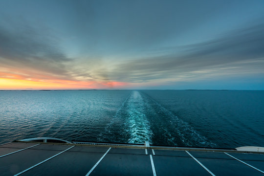 Beautiful sunset ocean view of the horizon with ship's wake seen from the back of a cruise ship.