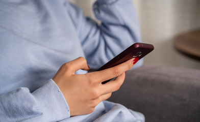 Young woman is using phone from home during quarantine time at coronavirus