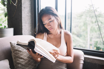 Asian woman reading book at home