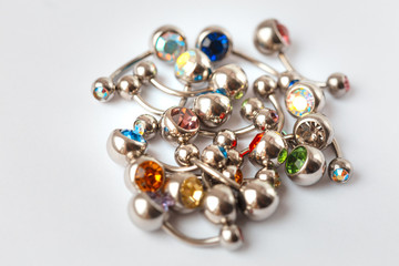 A mix of different multicolored navel piercing earrings - red, orange, yellow, green, blue, indigo blue and purple. Macro closeup