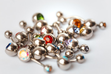 A mix of different multicolored navel piercing earrings - red, orange, yellow, green, blue, indigo blue and purple. Macro closeup