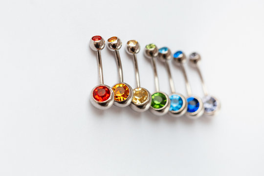 7 multicolored navel piercing earrings - red, orange, yellow, green, blue, indigo blue and purple. Macro closeup. Different focus points