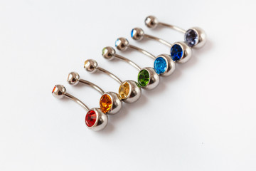 7 multicolored navel piercing earrings - red, orange, yellow, green, blue, indigo blue and purple. Macro closeup. Different focus points