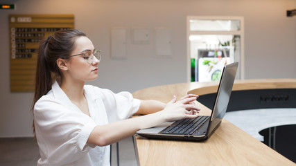 Fototapeta premium student sits at a table and uses a laptop, studying and working on the Internet.