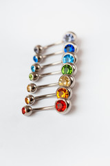 7 multicolored navel piercing earrings - red, orange, yellow, green, blue, indigo blue and purple. Macro closeup. Different focus points