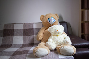 Generic bear toy in couch wearing handmade paper mask - lockdown covid-19