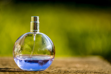 Obraz na płótnie Canvas Perfume bottle on wooden table at sunset.