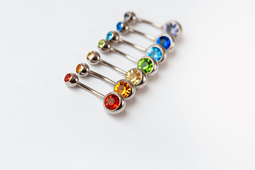 7 multicolored navel piercing earrings - red, orange, yellow, green, blue, indigo blue and purple. Macro closeup. Different focus points