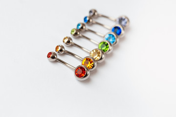 7 multicolored navel piercing earrings - red, orange, yellow, green, blue, indigo blue and purple. Macro closeup. Different focus points