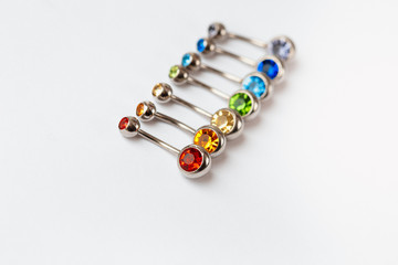 7 multicolored navel piercing earrings - red, orange, yellow, green, blue, indigo blue and purple. Macro closeup. Different focus points