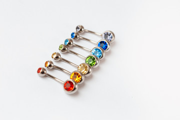7 multicolored navel piercing earrings - red, orange, yellow, green, blue, indigo blue and purple. Macro closeup. Different focus points