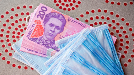 Medical masks with money. Ukrainian money with protective masks. A fan of Ukrainian hryvnia with a fan of medical masks.