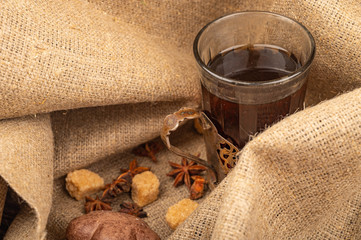 A faceted glass of tea in a vintage Cup holder, bagels, cookies, chocolate and chocolate cakes on a background of rough homespun fabric. Close up.