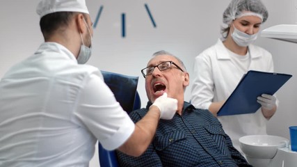 Male dentist looking x ray shot of mouth cavity to mature patient. Medium shot on RED camera - Powered by Adobe