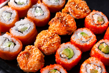 set of Japanese rolls  California with caviar,   Philadelphia with salmon, baked with  eel and . cheese , on a black background close-up, many sushi ,