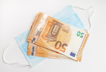 Euro banknotes and a protective mask against coronavirus.