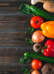 red and yellow peppers, green cucumbers, garlic, beetroot, tomato, spinach, potatoes,  onions,   on a brown wooden  top view, fresh vegetables, copy space