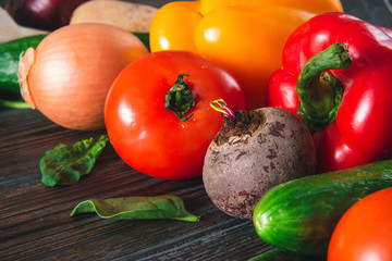 red tomato,  yellow peppers, green cucumbers, garlic, beetroot,  onions, spinach  on a brown wooden  , fresh vegetables,  close up