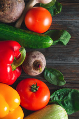 peppers, beetroot, tomato, green cucumbers,  spinach , garlic,  onions, on a brown wooden background top view, fresh vegetables,