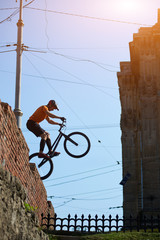 Vertical low angle snapshot of extreme rider making acrobatic stunt on the edge of brick wall....