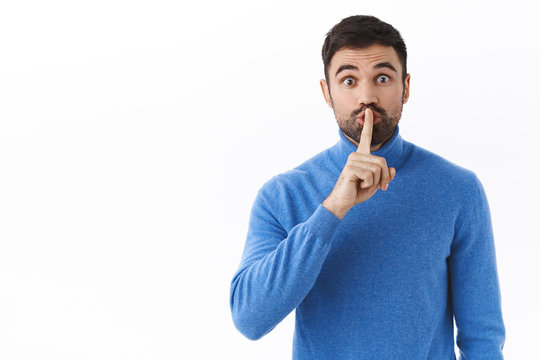 Shhh keep your voice down. Enthusiastic handsome caucasian guy prepare surprise, asking be quiet, shush at camera with index finger pressed to lips, need silence, standing white background