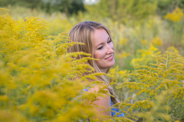 horizontal close-up portrait of a charming cute blonde in a blooming wild field