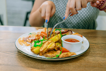 Female hands with knife and fork cut meat with potatoes. Female hands with manicure. Restaurant dish
