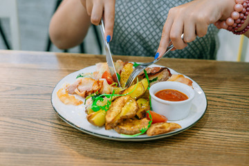Female hands with knife and fork cut meat with potatoes. Female hands with manicure. Restaurant dish