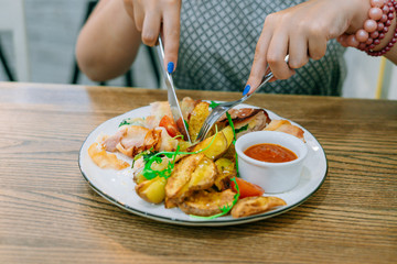 Female hands with knife and fork cut meat with potatoes. Female hands with manicure. Restaurant dish