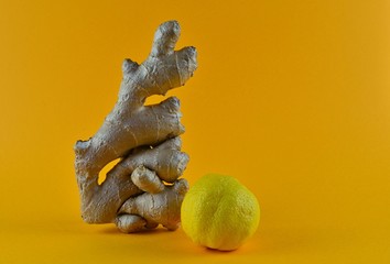Large piece of fresh Root Ginger and lemon on a yellow background. Fresh organic ginger