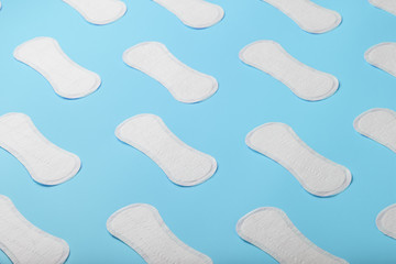 Many Sanitary pads on a blue background in the form of a diagonal pattern. Textured background all over the screen.
