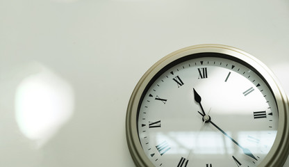 Classic clock on a white wall in the house. Close-up. Space for text