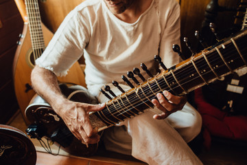 Close up photo of hands of an Indian musician playing a sitar