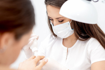 Manicure specialist applying glue for nail of woman close up. Manicurist using manicure tool.