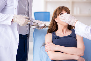 Two male doctors and young woman in plastic surgery concept