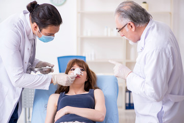 Fototapeta premium Two male doctors and young woman in plastic surgery concept