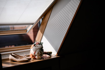 Bride's shoes and bouquet stand on the windowsill