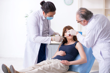 Two male doctors and young woman in plastic surgery concept