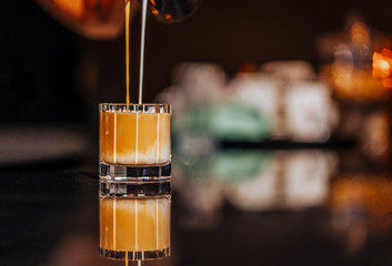 Iced americano preparation, pouring milk and coffee into iced glass