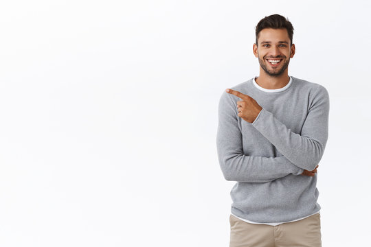 Man praising great concept, pointing left at your project as discuss corporate staff coworker. Attractive pleased businessman in grey casual sweater having chat and recommend check-out product