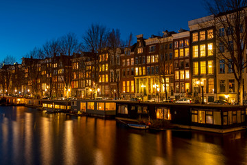 Obraz premium Traditional houses and houseboats in Amsterdam the Netherlands at sunset