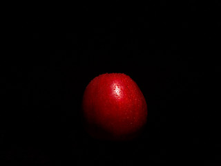 Juicy red apple covered with water droplets, photo on the black background in the light of the lamp - obrazy, fototapety, plakaty
