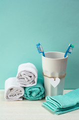 Turquoise bathroom. White a cotton toweles, toothbrushes in jar on turquoise backdrop. 
Personal care concept