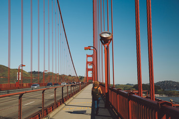 Rear View Of Mid Adult Woman With Backpack Walking On Golden Gate Bridge Against Clear Sky