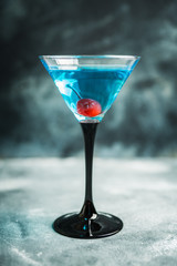 Blue martini cocktail with cherry on the rustic background. Selective focus. Shallow depth of field.