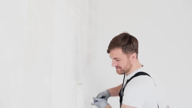 pretty master draws a white wall with a roller
