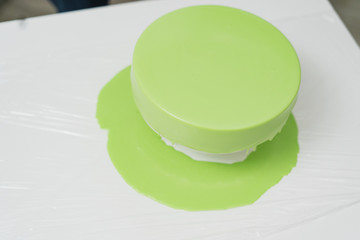 Pastry cook prepares a cake of green, watering it with icing